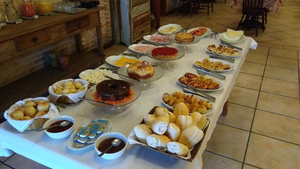 A buffet table with various food items and condiments. - Pousada Chablis (Campos do Jordão)