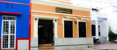 A hotel named Solymar with a signboard, a number 19-06, and a motorcycle parked outside.