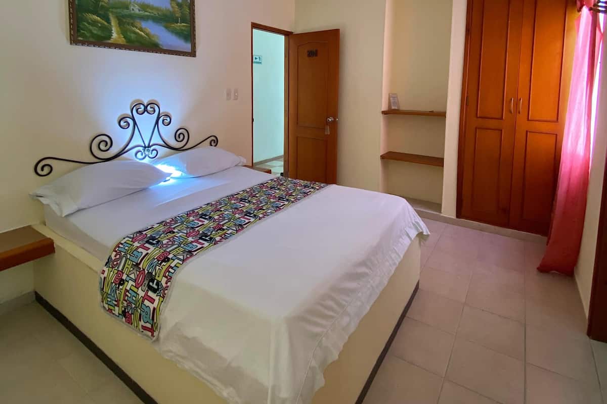 Un dormitorio con cama, un cuadro en la pared, una puerta y un armario.
