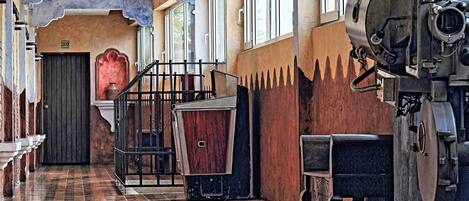 A corridor with a tiled floor, a large arched doorway, and a vintage camera on the right.