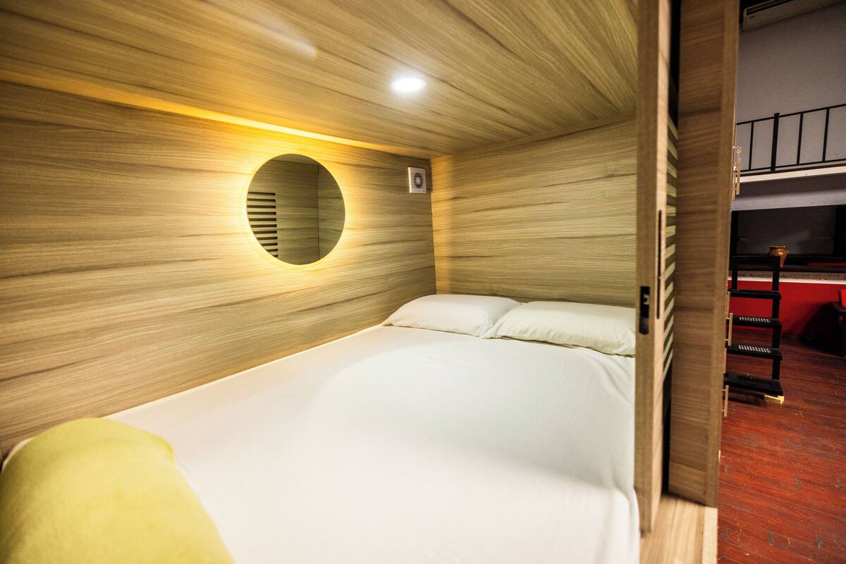 A single bed with a circular wall feature and a red wall in the background.