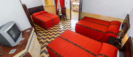Una habitación con dos camas, televisión y suelo estampado.