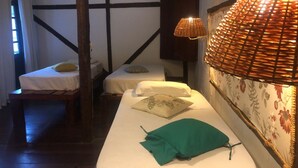 A room with two single beds, a bench, a lamp, and a floral wallpaper. - Palma Hostel (São Luís)