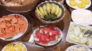 A buffet table with various fruits and pastries. - Palma Hostel (São Luís)