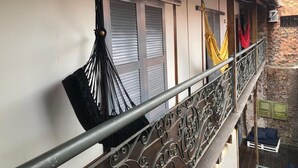 A balcony with a wrought iron railing, a hammock, and a small seating area with cushions. - Palma Hostel (São Luís)