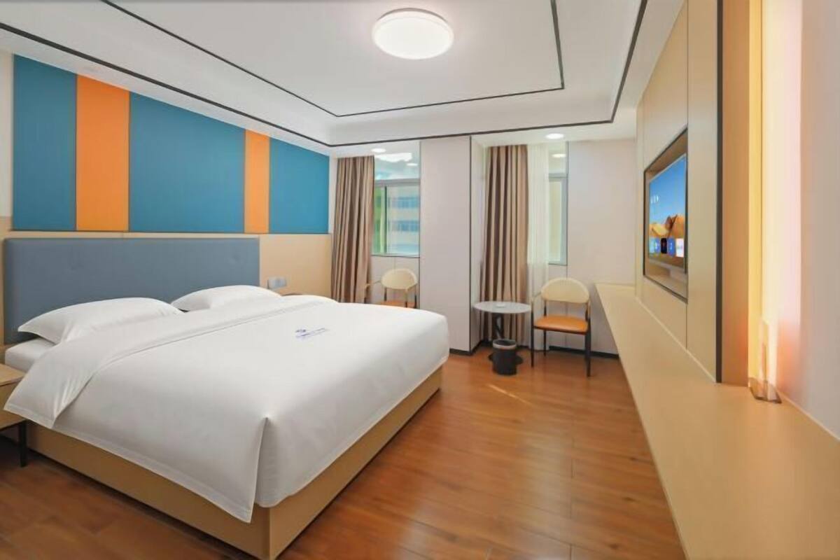 Una habitación de hotel con cama, una mesita, una silla y televisión.