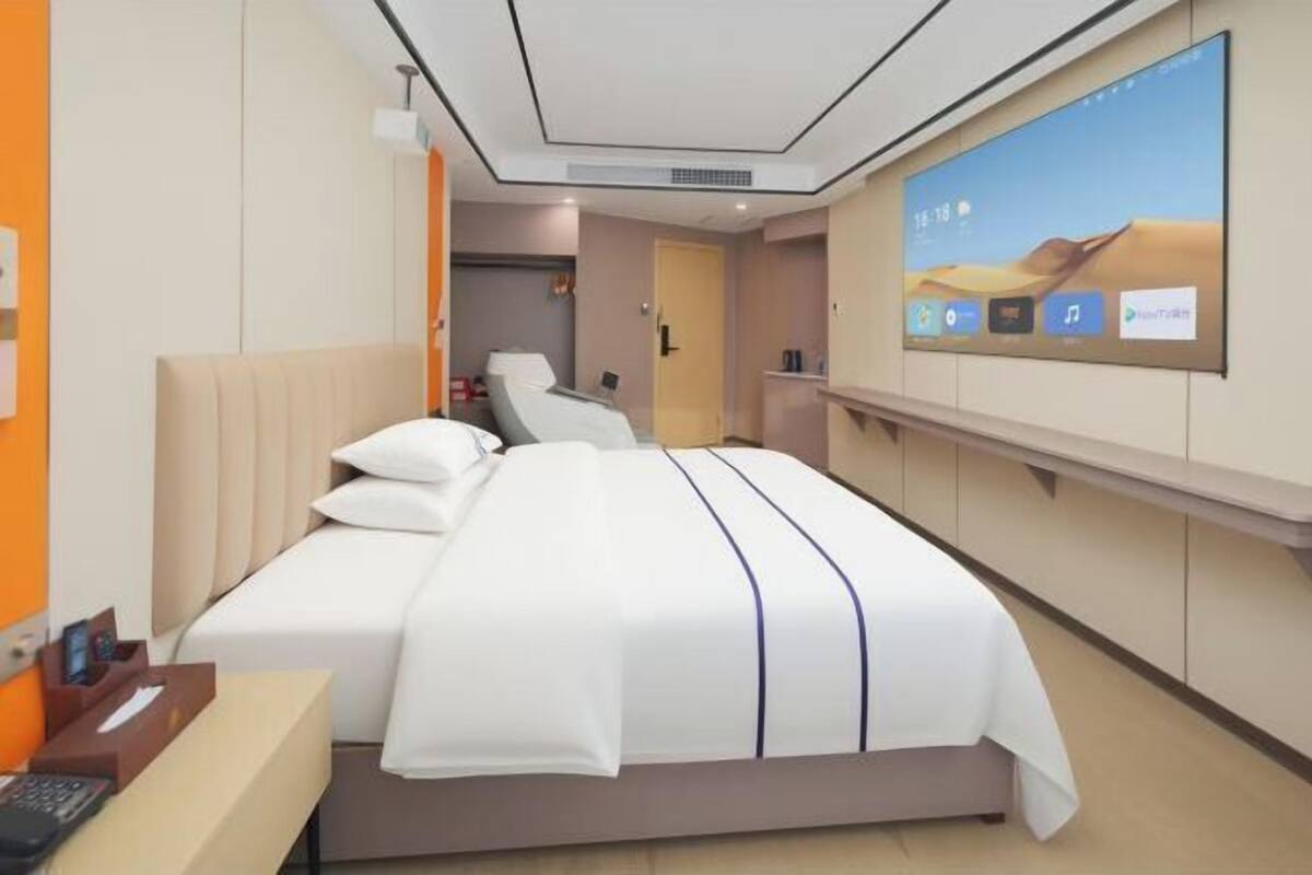 Una habitación de hotel con cama, televisión y escritorio con teléfono.
