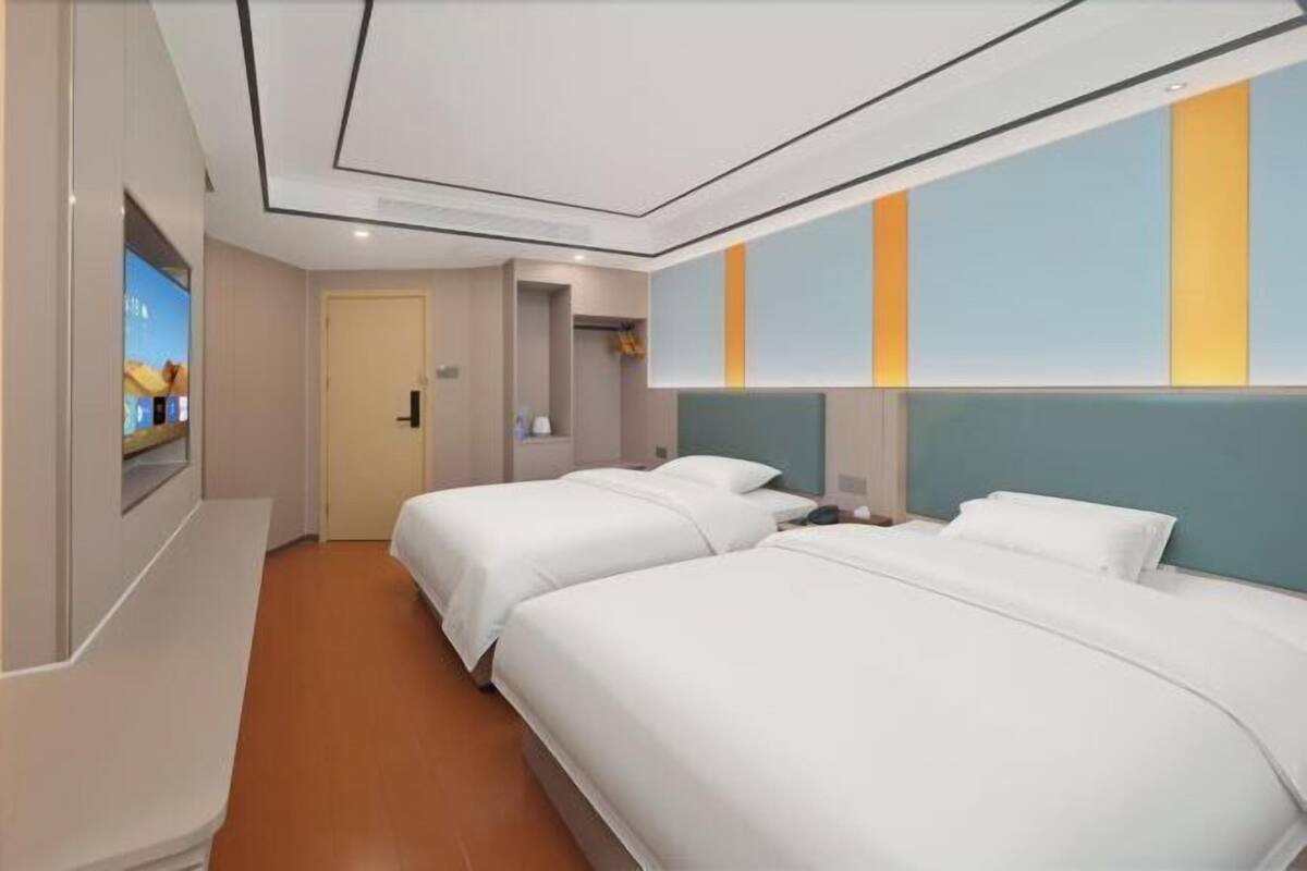 Habitación de hotel con dos camas, un televisor y una pared de rayas verticales.