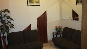 A living room with two sofas, a potted plant, a small table with a vase, and a framed picture on the wall. - Hotel Plaza Bolognesi (Trujillo)