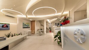 A modern reception area with a reception desk, seating area, and a staircase leading to an upper level.