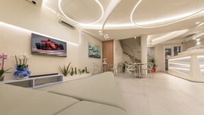 A modern interior with a sofa, a dining area, and a staircase.