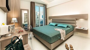 A modern hotel room with a large bed, a desk with a lamp, a chair, a handbag, and a pair of sandals on the floor.