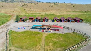 Un camping con varias cabañas, mesas de picnic y una zona de estar cubierta.