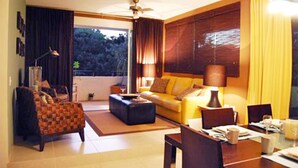 A spacious living room with a sofa, armchairs, a coffee table, and a dining table. - Meridian 202 by PRP (Playa del Carmen)