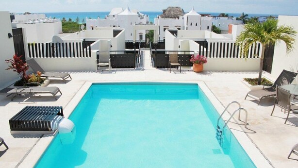 A rooftop pool with a clear view of the ocean and white buildings in the background. - Meridian 202 by PRP (Playa del Carmen)