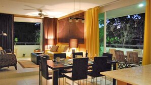 A modern living room with a dining area, large windows, and a ceiling fan. - Meridian 202 by PRP (Playa del Carmen)