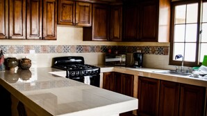 A kitchen with wooden cabinets, a stove, a microwave, and a sink. - Maison Bougainvillea (Antigua Guatemala)