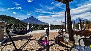 A covered outdoor area with a hammock, a table, and a view of a mountain. - Maison Bougainvillea (Antigua Guatemala)