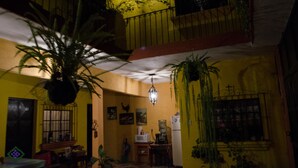 A room with yellow walls, a ceiling fan, and hanging plants. - Maison Bougainvillea (Antigua Guatemala)