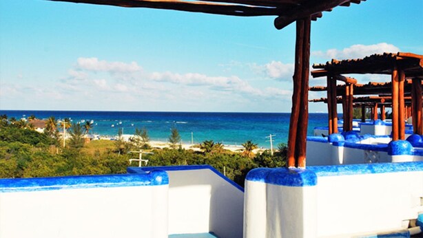 A beachside view with a wooden pergola and white walls with blue trim. - Natz Ti Ha A301 by PRP (Playa del Carmen)