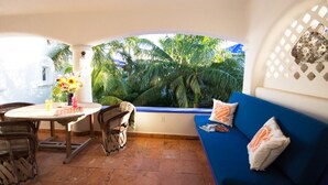 A cozy patio area with a round table, chairs, and a blue sofa with decorative pillows. - Natz Ti Ha A301 by PRP (Playa del Carmen)