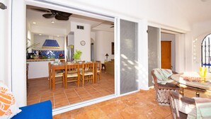 A spacious living area with a dining table and chairs, a sofa, and a sliding glass door leading to a kitchen. - Natz Ti Ha A301 by PRP (Playa del Carmen)