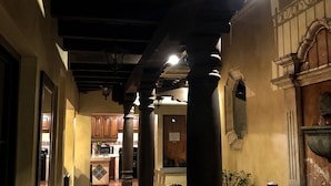 Un couloir orné de colonnes en bois, un coin cuisine avec des placards et une fontaine en pierre.
