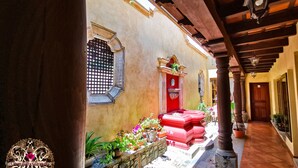 Une cour avec un banc rouge, des plantes en pot et un mur de pierre.