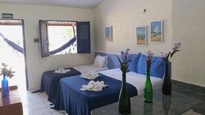 A hotel room with two beds, a dining table, and a window with a view. - Pousada Vila do Mar (Sao Jose de Ribamar)