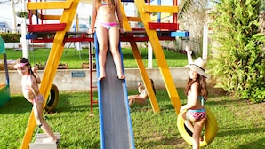 A playground with a slide and swings. - Pousada Vila do Mar (Sao Jose de Ribamar)