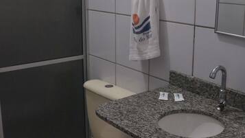 Un bagno con il water, un lavandino e un asciugamano appeso al muro.