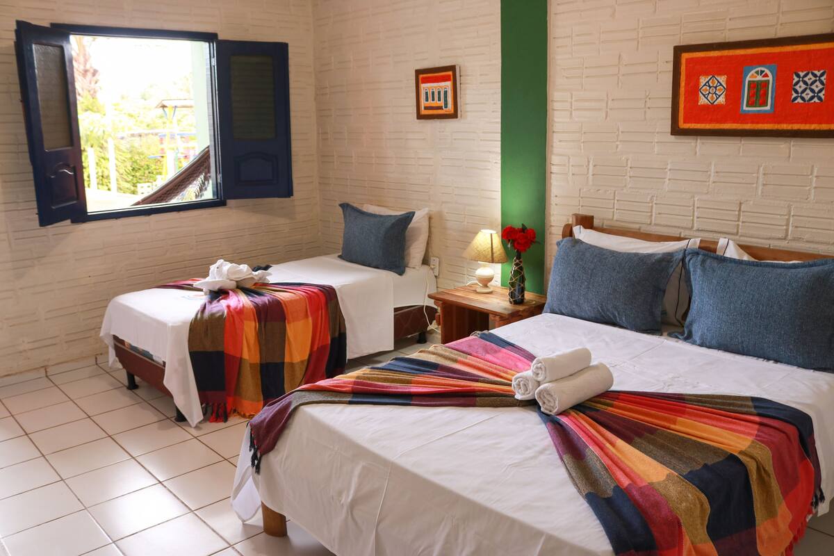 A hotel room with two beds, a window, a green wall, and a framed picture.