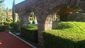 A stone archway with a red pathway leading through a well-maintained garden. - Quinta Huizache (Nopaltepec)