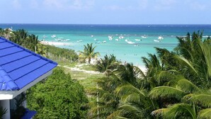 Blick auf einen Strand mit Booten, Palmen und blauem Himmel.