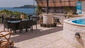 An outdoor patio area with a pool, seating, and a covered barbecue area. - Monte Perla Residence (Sveti Stefan)