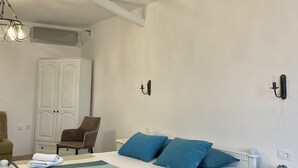 A bedroom with a bed, a chair, a dresser, and a chandelier. - Monte Perla Residence (Sveti Stefan)
