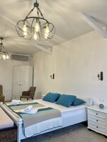 A bedroom with a bed, a chair, a dresser, and a chandelier.