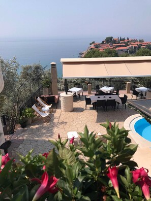 Une terrasse avec des sièges extérieurs, une piscine et une vue sur la mer.