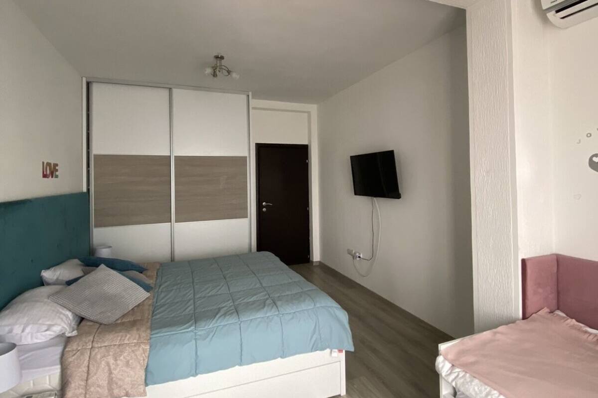 Um quarto com uma cama, uma TV, ar condicionado e um guarda-roupa.