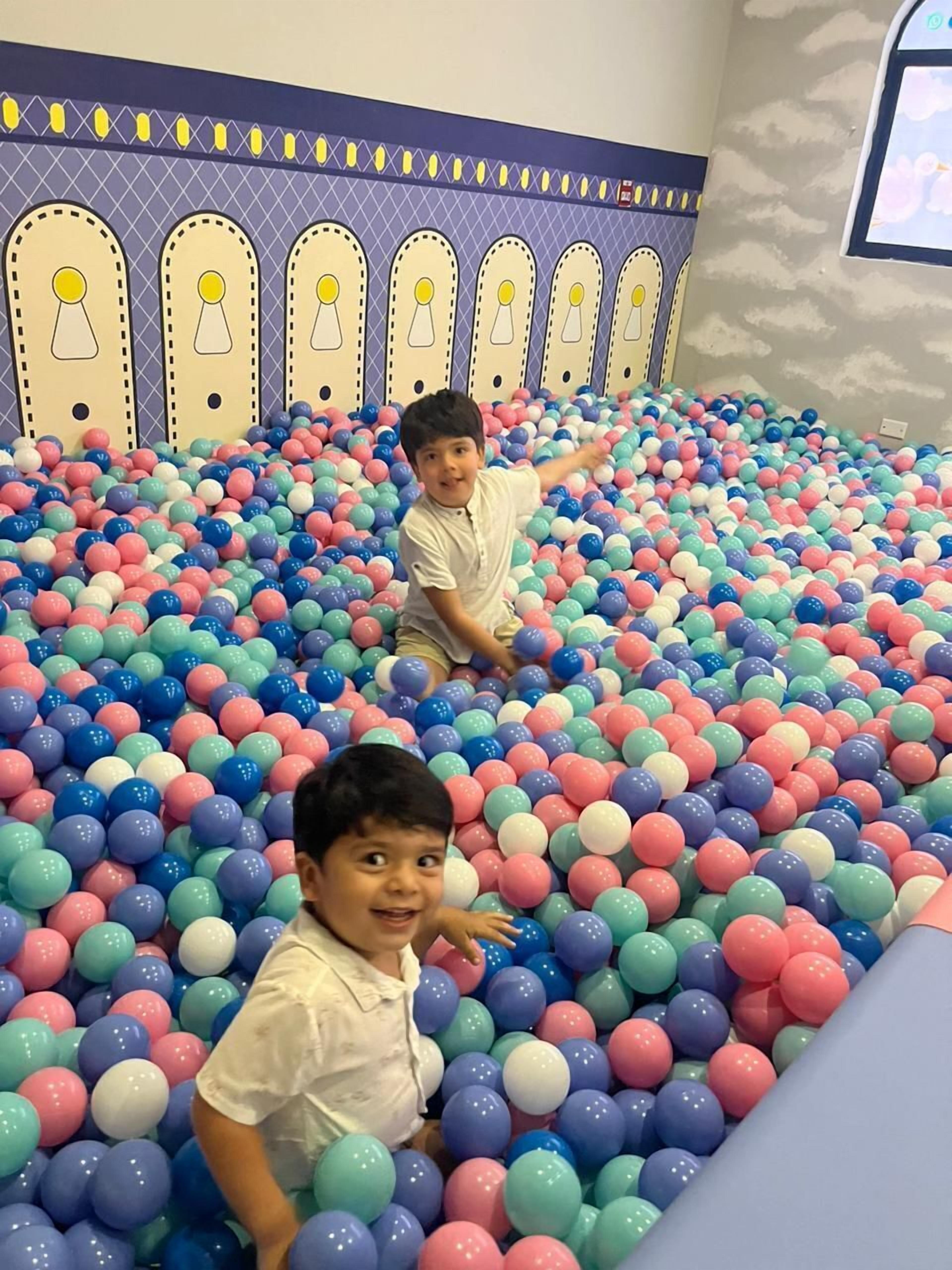 Dos niños jugando en una piscina de pelotas llena de bolas multicolores.