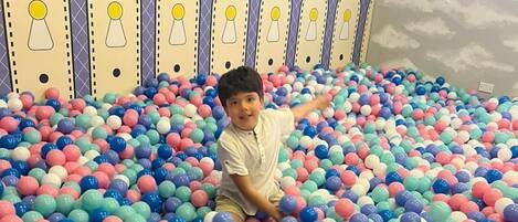 Dos niños jugando en una piscina de pelotas llena de bolas multicolores.