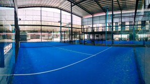 Una cancha deportiva interior con piso azul y paredes de vidrio.
