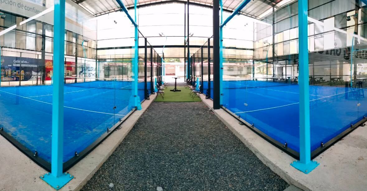 An indoor sports facility with a central court surrounded by seating and blue padded walls.