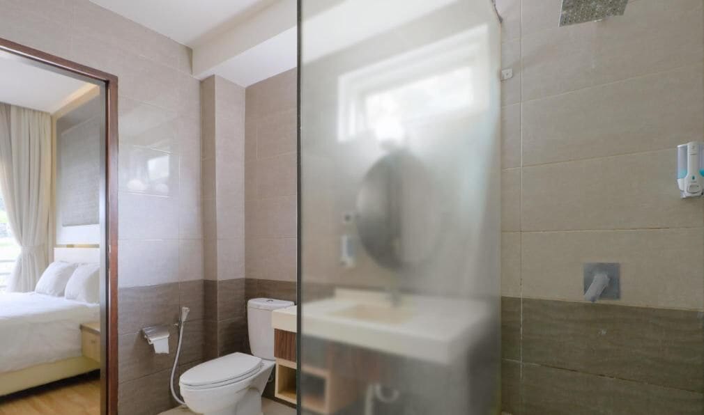 Een moderne badkamer met een glazen douchecabine, toilet en wastafel.