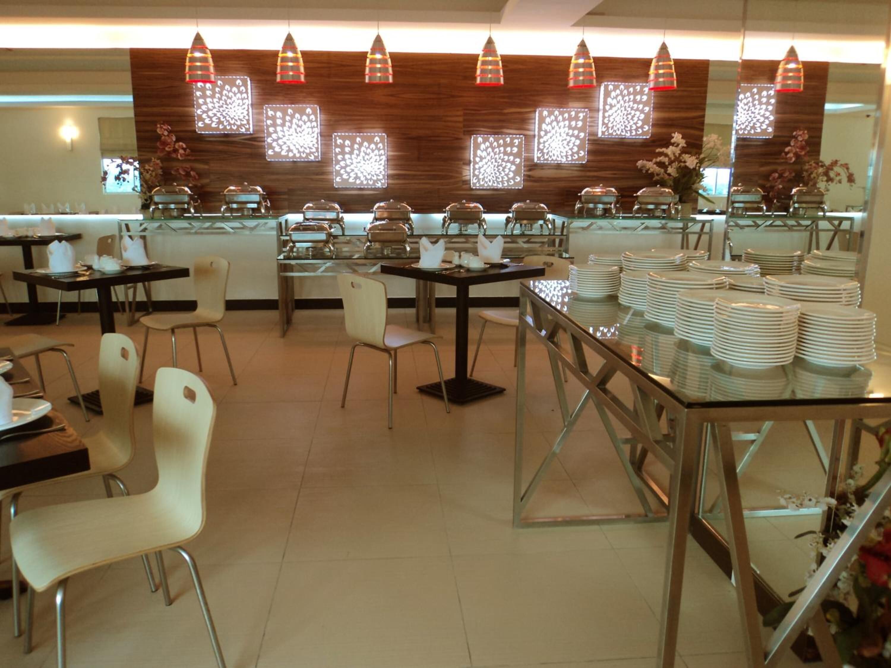 A restaurant with multiple tables and chairs, decorative wall panels, and hanging pendant lights.