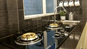 A kitchen with a gas stove, a sink, and a window. - Tehel Farmhouse (Jasin)