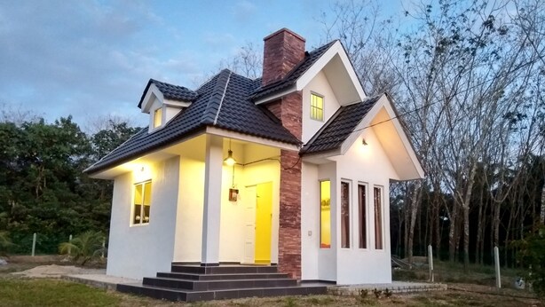 A single-story house with a gabled roof, a brick chimney, and a front porch with steps. - Tehel Farmhouse (Jasin)
