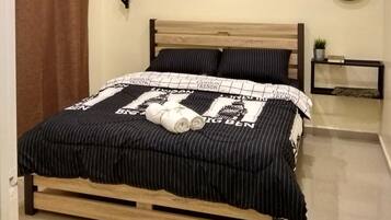 Un dormitorio con una cama, aire acondicionado, un cuadro, un espejo y una pequeña estantería con una planta.