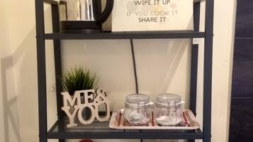 A kitchen shelf with a sign titled "Kitchen Rules," jars, a coffee maker, and a clapperboard.