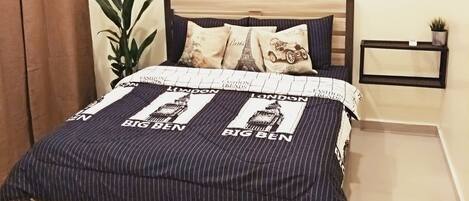 A bedroom with a bed, a nightstand, a potted plant, a wall-mounted mirror, and a painting of a cityscape.